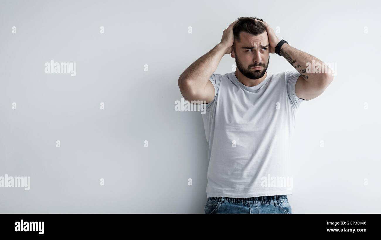 What to do. Negative emotions, disappointed, guilt, upset, confused person, something bad. Sad unhappy pensive young handsome man hold his head with h Stock Photo