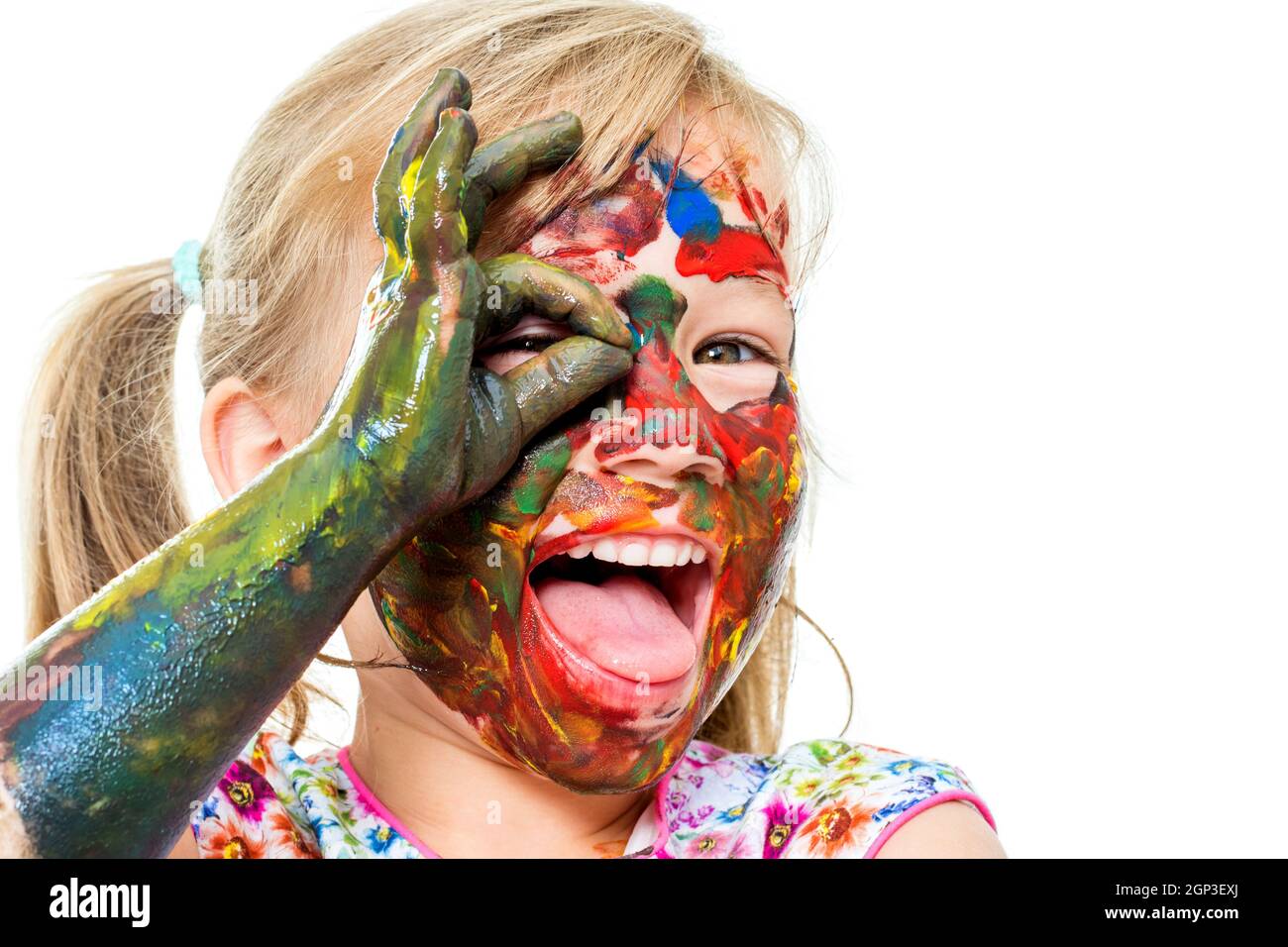 Close up portrait of little girl covered with color paint and open mouth. Face shot of infant doing okay sigh in front of eye.Isolated on white backgr Stock Photo