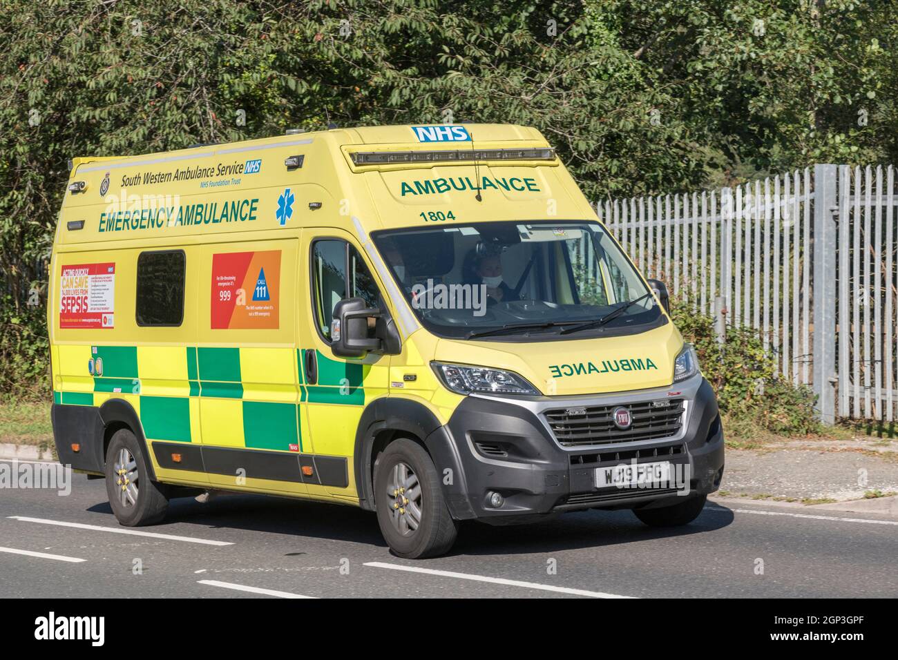 Official NHS yellow ambulance / emergency paramedic crew on rural road
