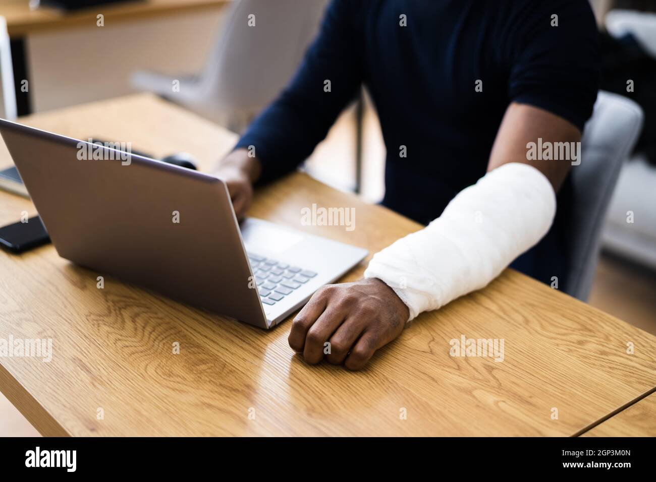 Injured Worker Compensation. Broken Arm African Man On Computer Stock Photo