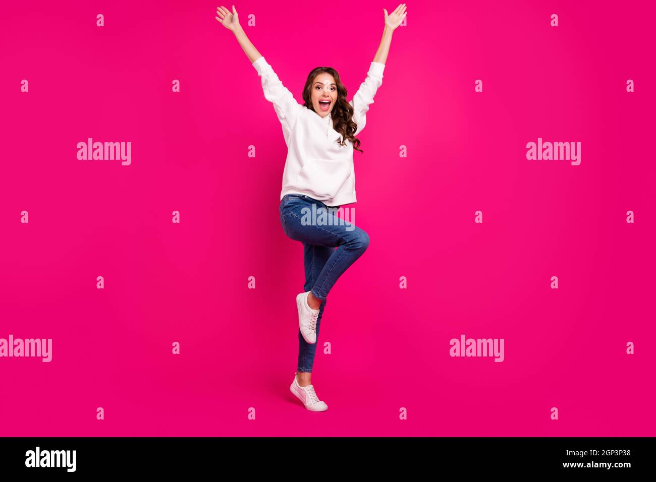 Photo of excited amazed crazy lady raise hands wear white hoodie jeans footwear isolated pink color background Stock Photo