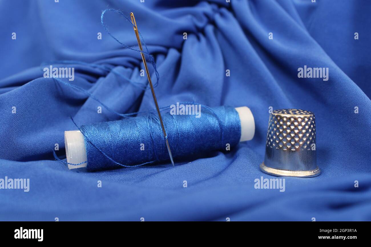 Thimble and Blue Thread on Blue Fabric Stock Photo