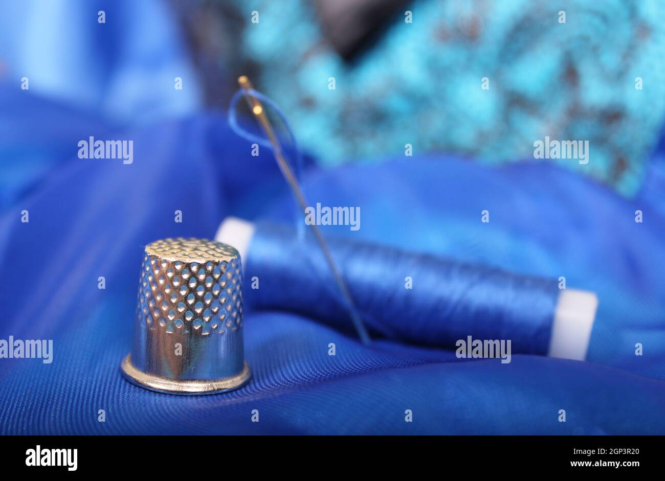 Thimble and Blue Thread on Blue Fabric Stock Photo