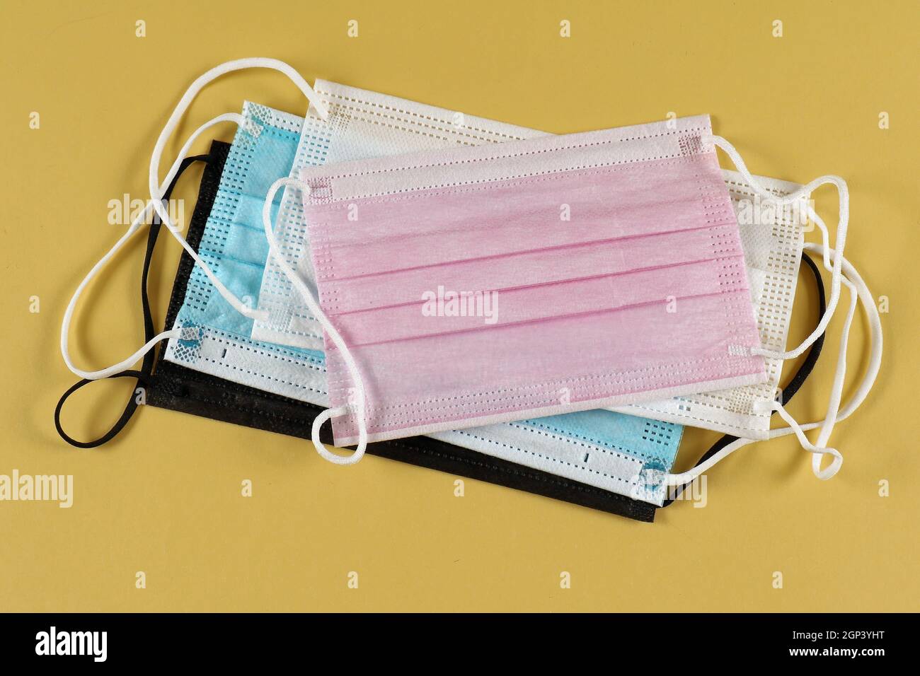Multicoloured disposable face masks stack for protection against respiratory viruses Stock Photo