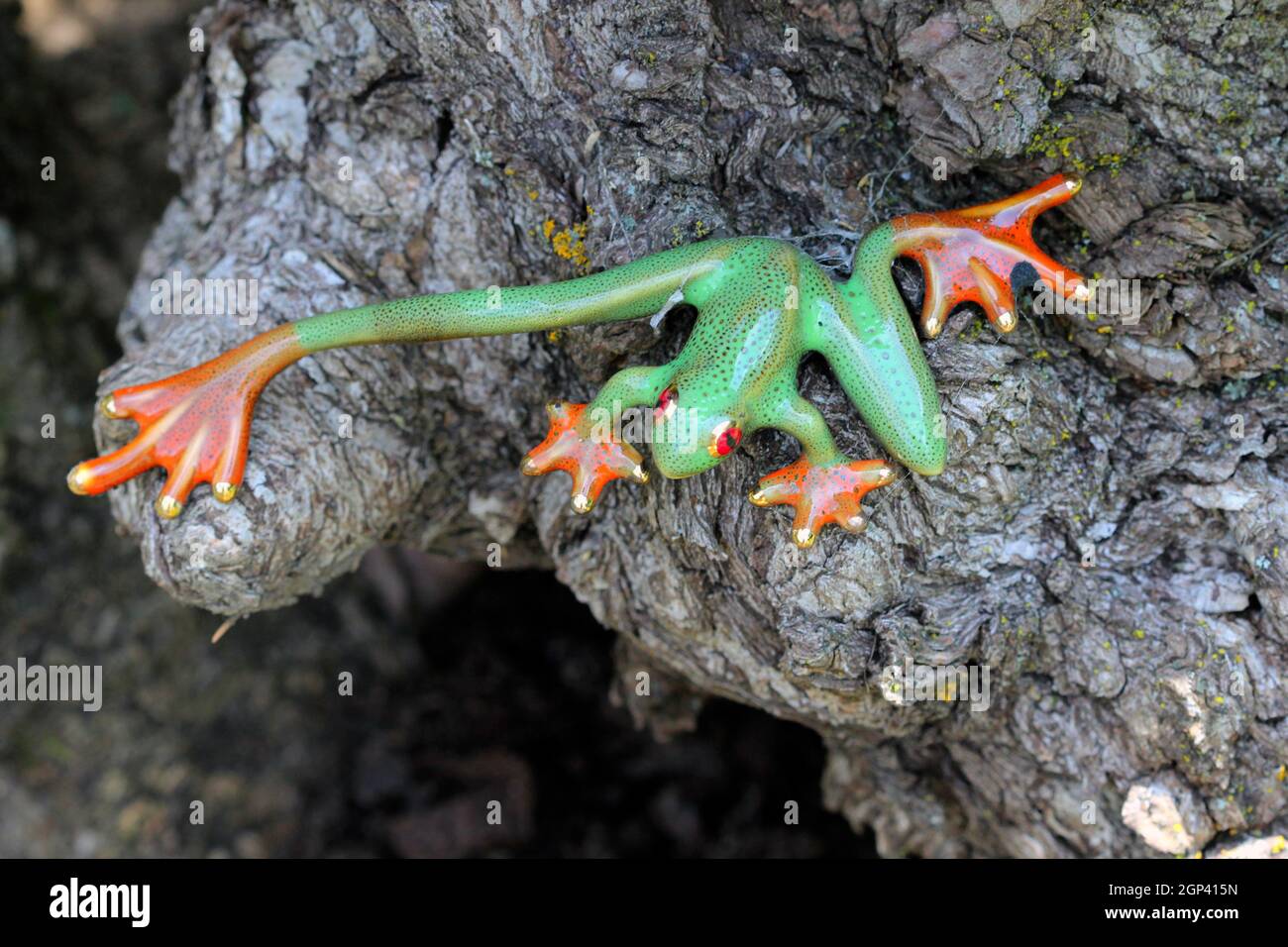 This ornamental green frog statue with orange feet is decorated with tiny small black spots. Stock Photo