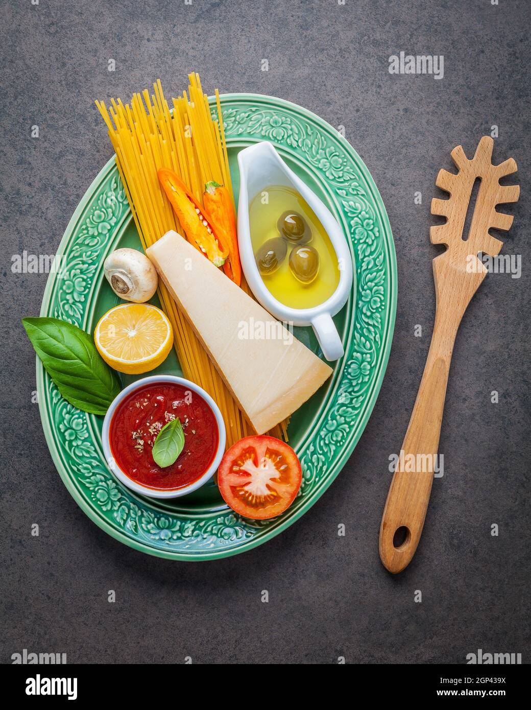 Italian food and menu concept. Spaghetti with ingredients sweet basil ,tomato ,garlic peppercorn and champignon on dark background flat lay and copy s Stock Photo