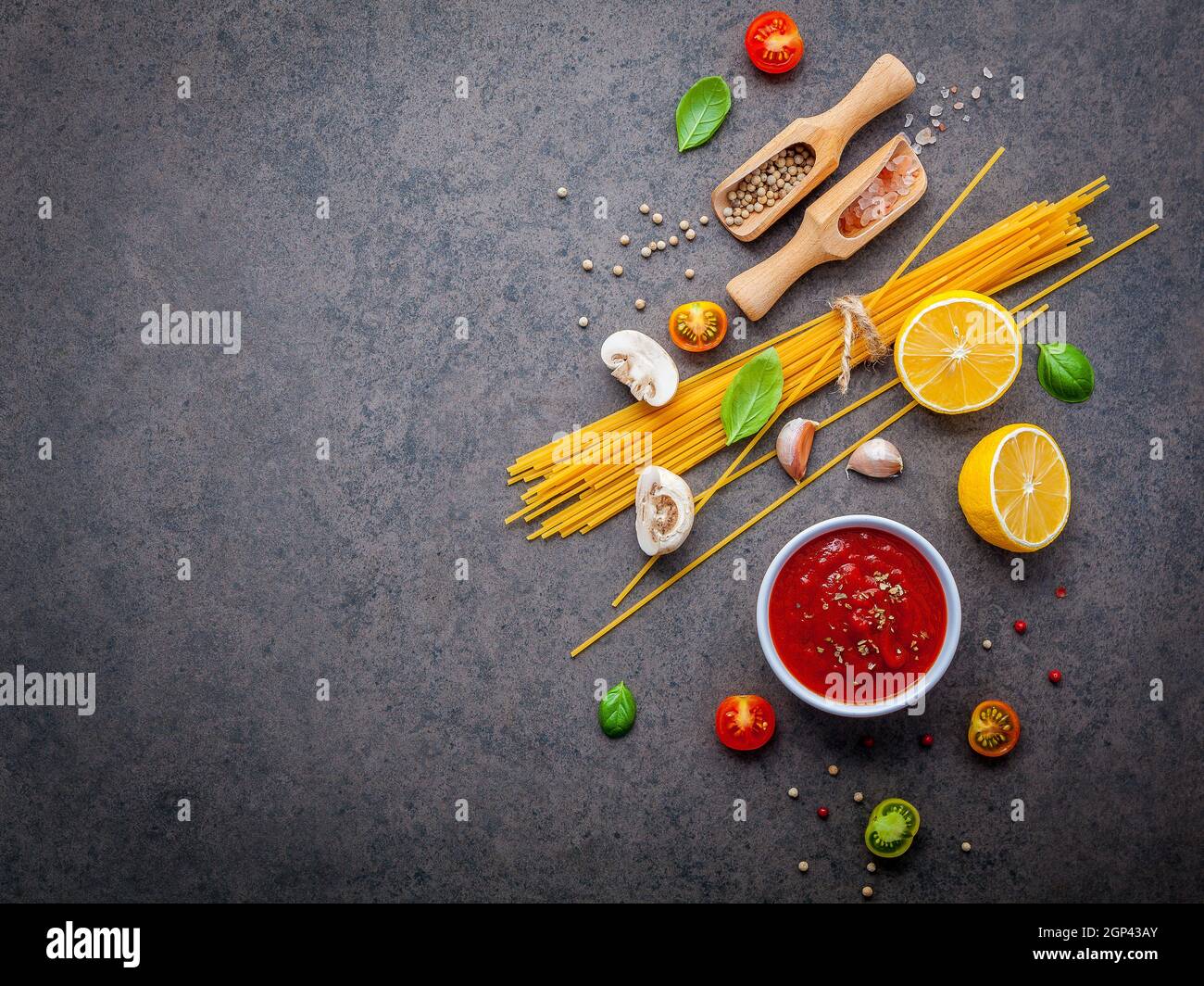 Italian food and menu concept. Spaghetti with ingredients sweet basil ,tomato ,garlic peppercorn and champignon on dark background flat lay and copy s Stock Photo
