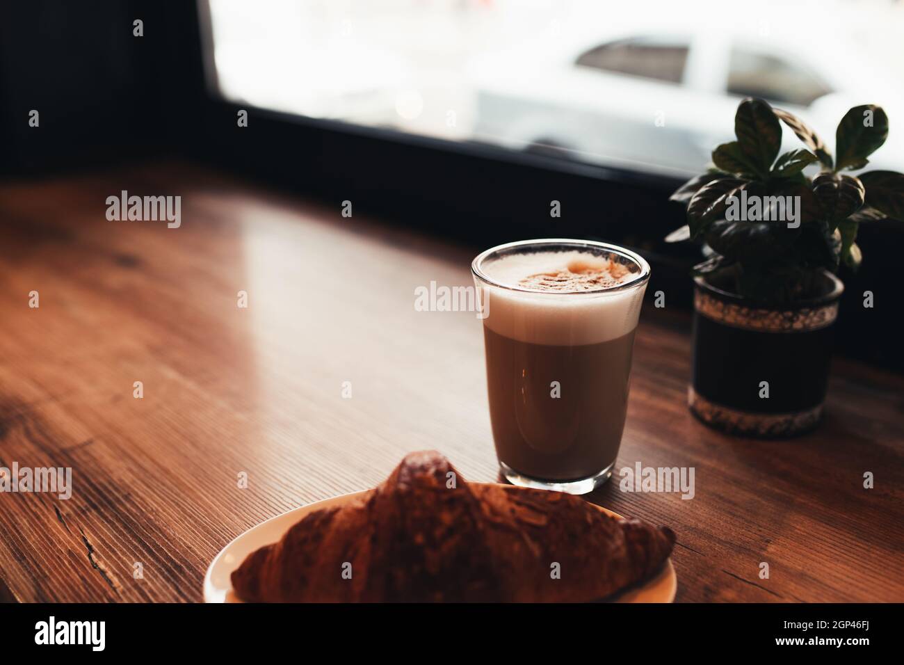 Cup of coffee, croissant at table near the window in cafe. Blurred ...