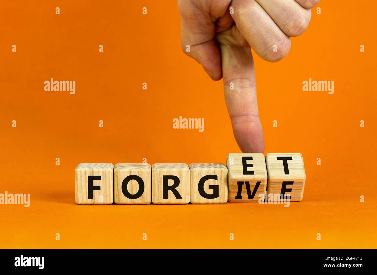 Forgive and forget symbol. Businessman turns wooden cubes and changes the word 'forgive' to 'forget'. Beautiful orange background, copy space. Busines Stock Photo