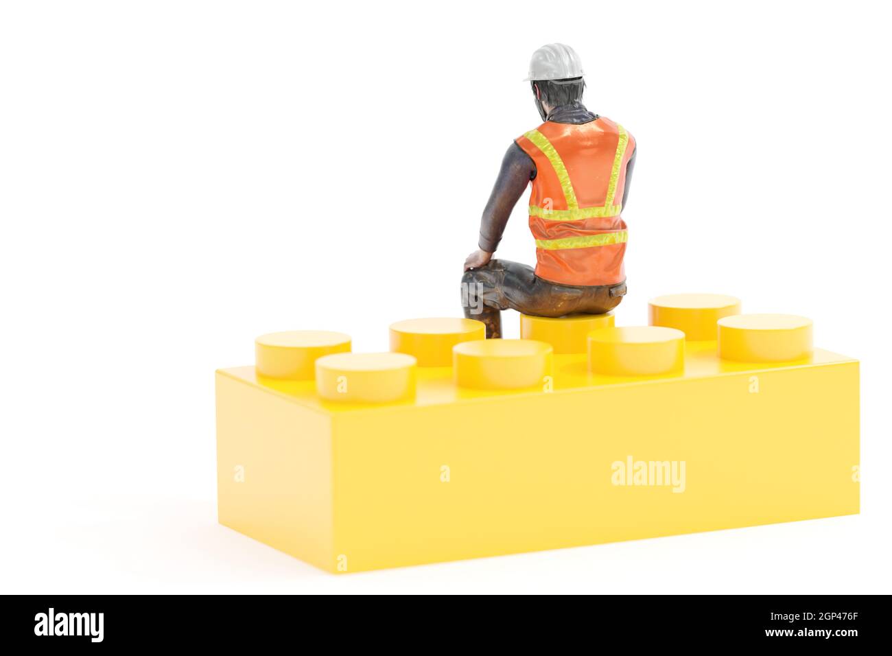 Miniature worker with safety gear sitting on yellow toy brick against white background Stock Photo