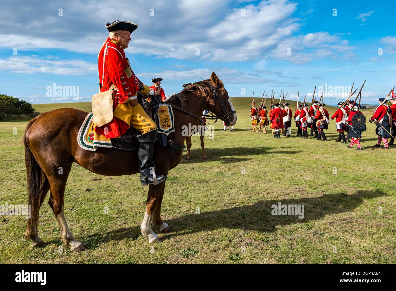 Hanoverian redcoat soldiers in period costume march with officer on horse in re-enactment of Battle of Prestonpans, East Lothian, Scotland, UK Stock Photo