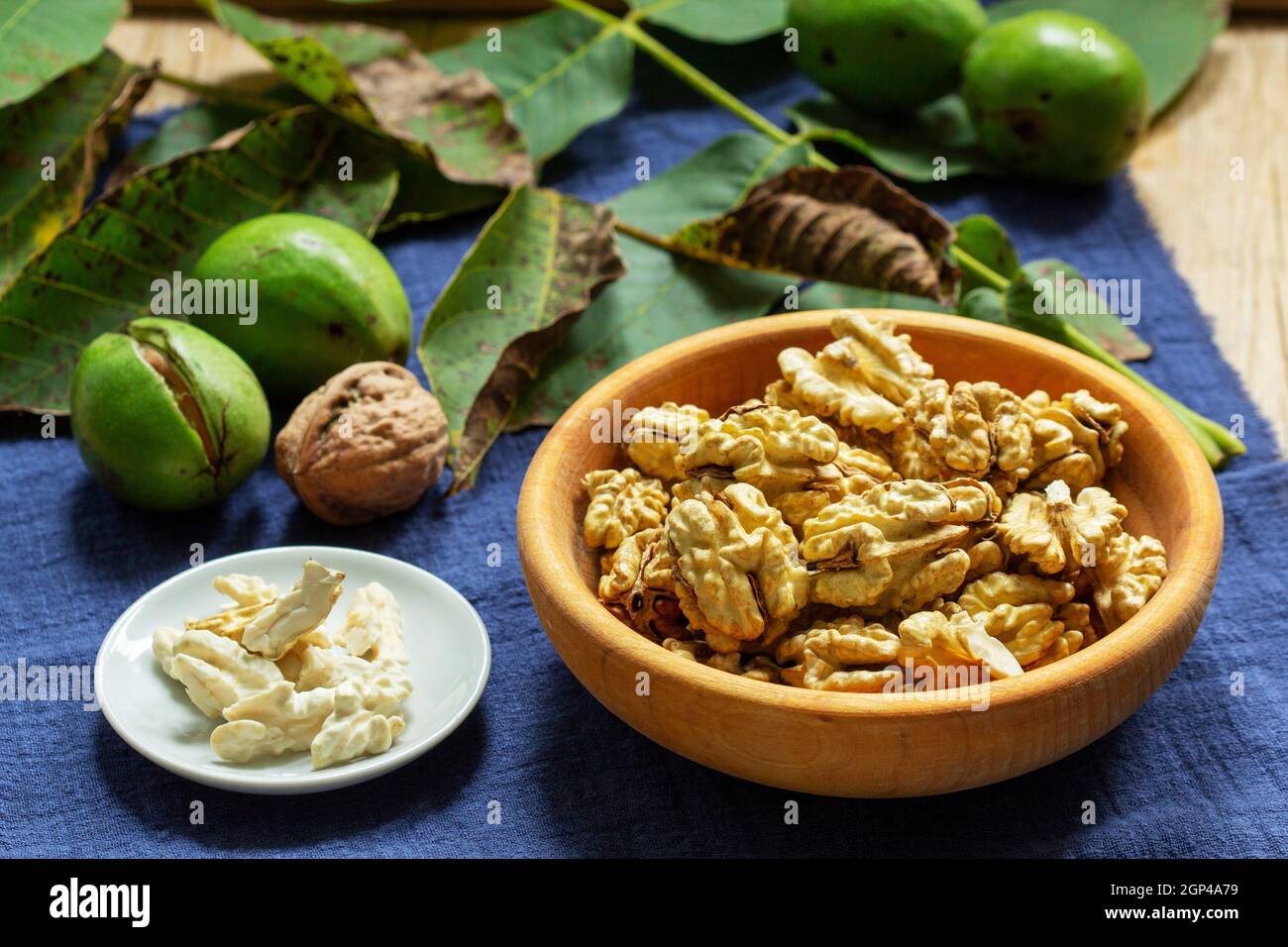 Young walnuts, shelled and in shell, walnut leaves. Rustic style. Stock Photo