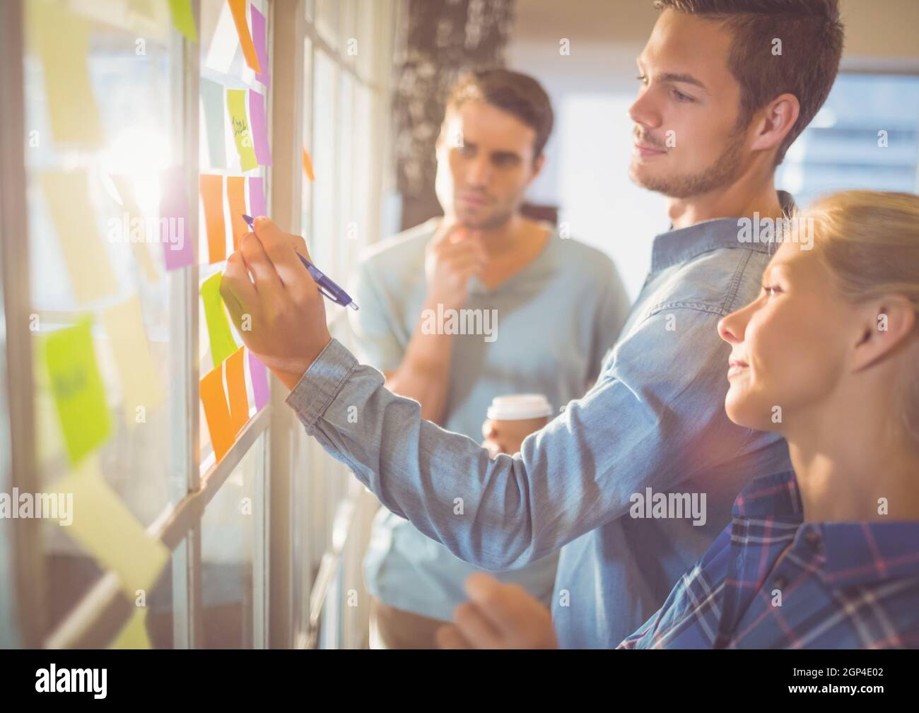 Composition of caucasian business people taking notes on glass wall Stock Photo