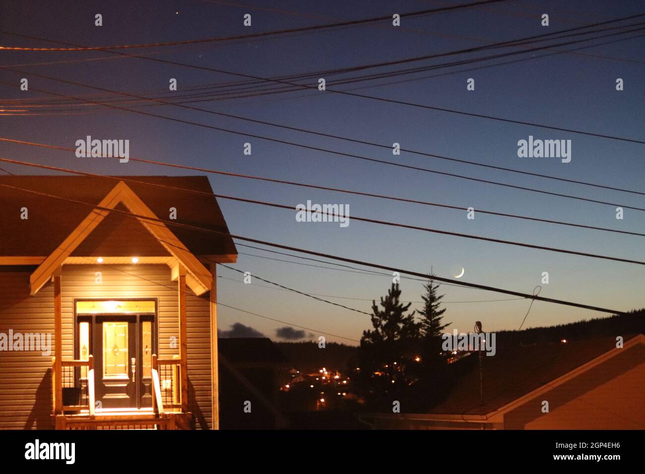Evening sky with a beautiful, well-lit house, the north star, and the moon. Stock Photo