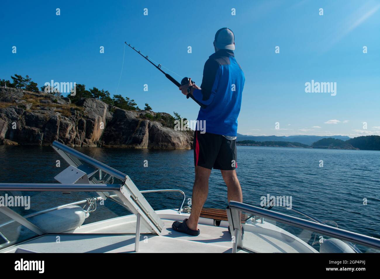 Male Fisherman with fishing rod on a boat in the ocean near Stavanger Norway (jig fishing) Stock Photo