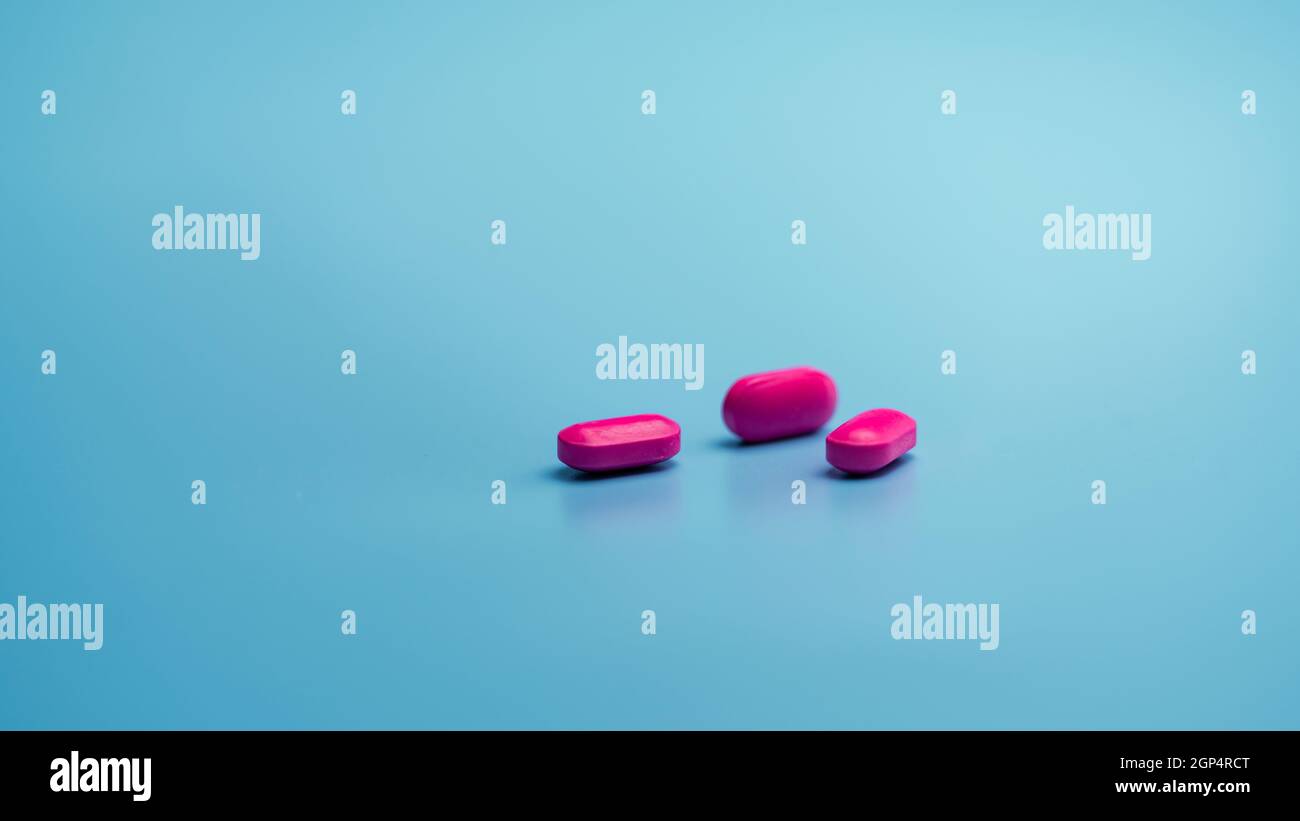 Pink tablets on blue background. Painkiller medicine. Ibuprofen tablets  pills. Pharmaceutical industry. Drug for treatment migraine headache.  Communit Stock Photo - Alamy