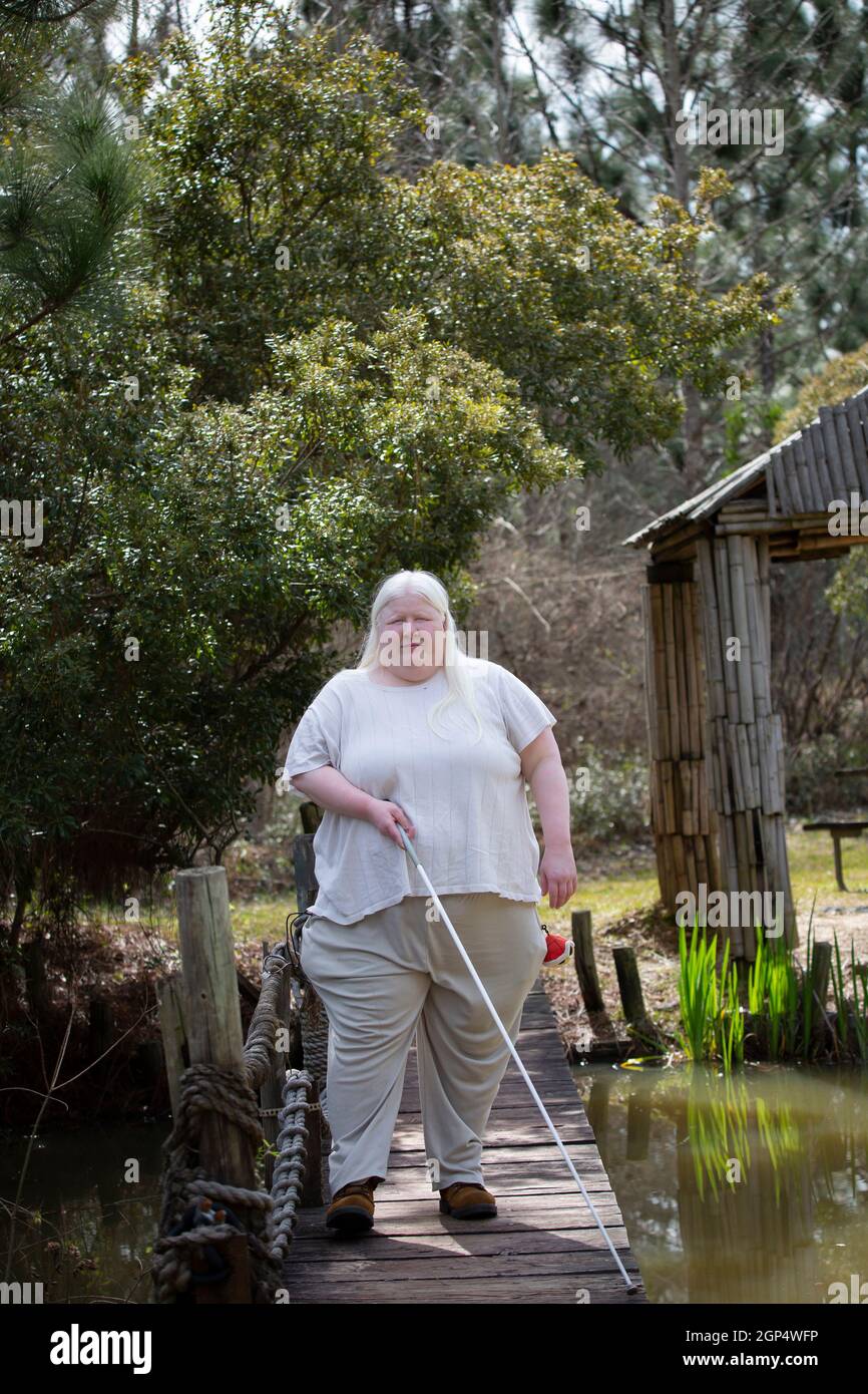 Happy blind woman on a wooden bridge over a pond with her eyes shut Stock Photo