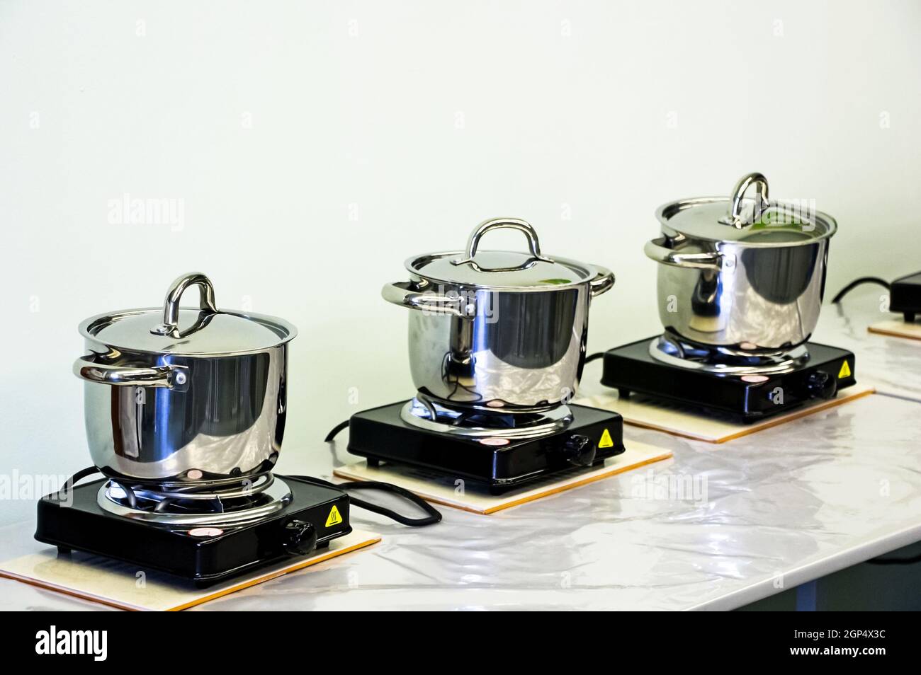 Steel pots on electric stoves. Cooking in pans Stock Photo Alamy