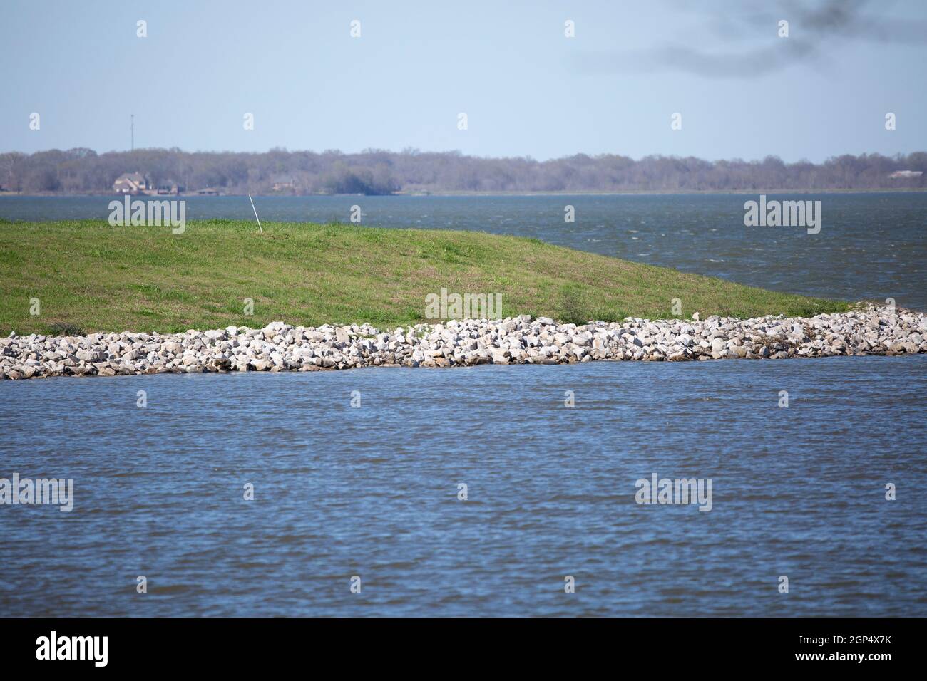 Green grass lined with large gravel rocks jutting into a lake Stock ...