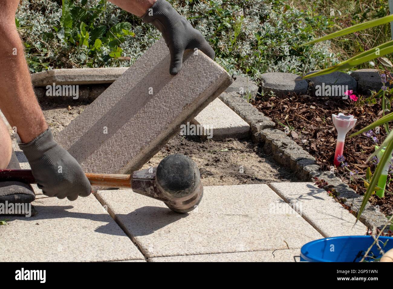 A professional paver worker laying patio slabs in a gravel bed using a