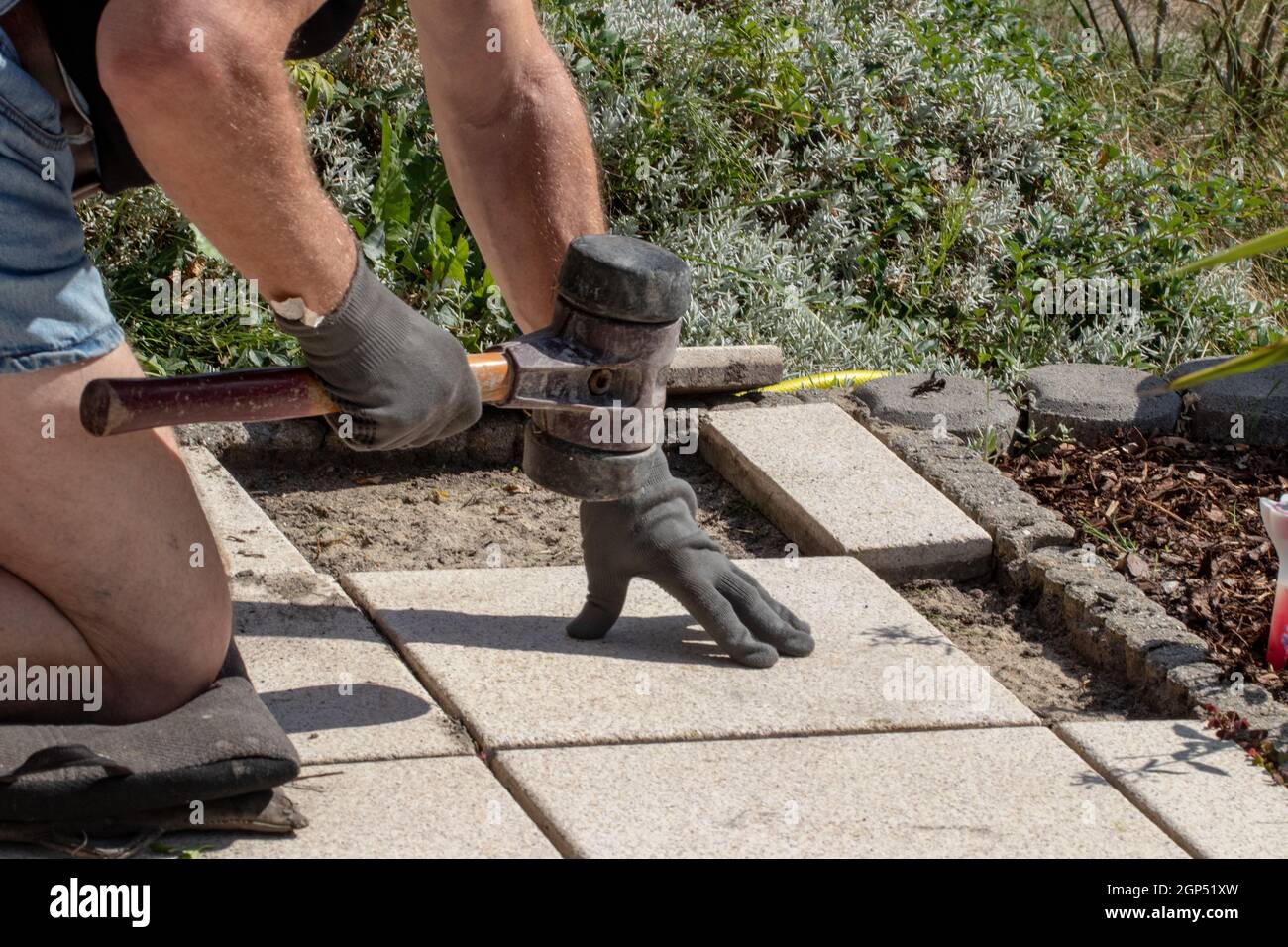 A professional paver worker laying patio slabs in a gravel bed using a