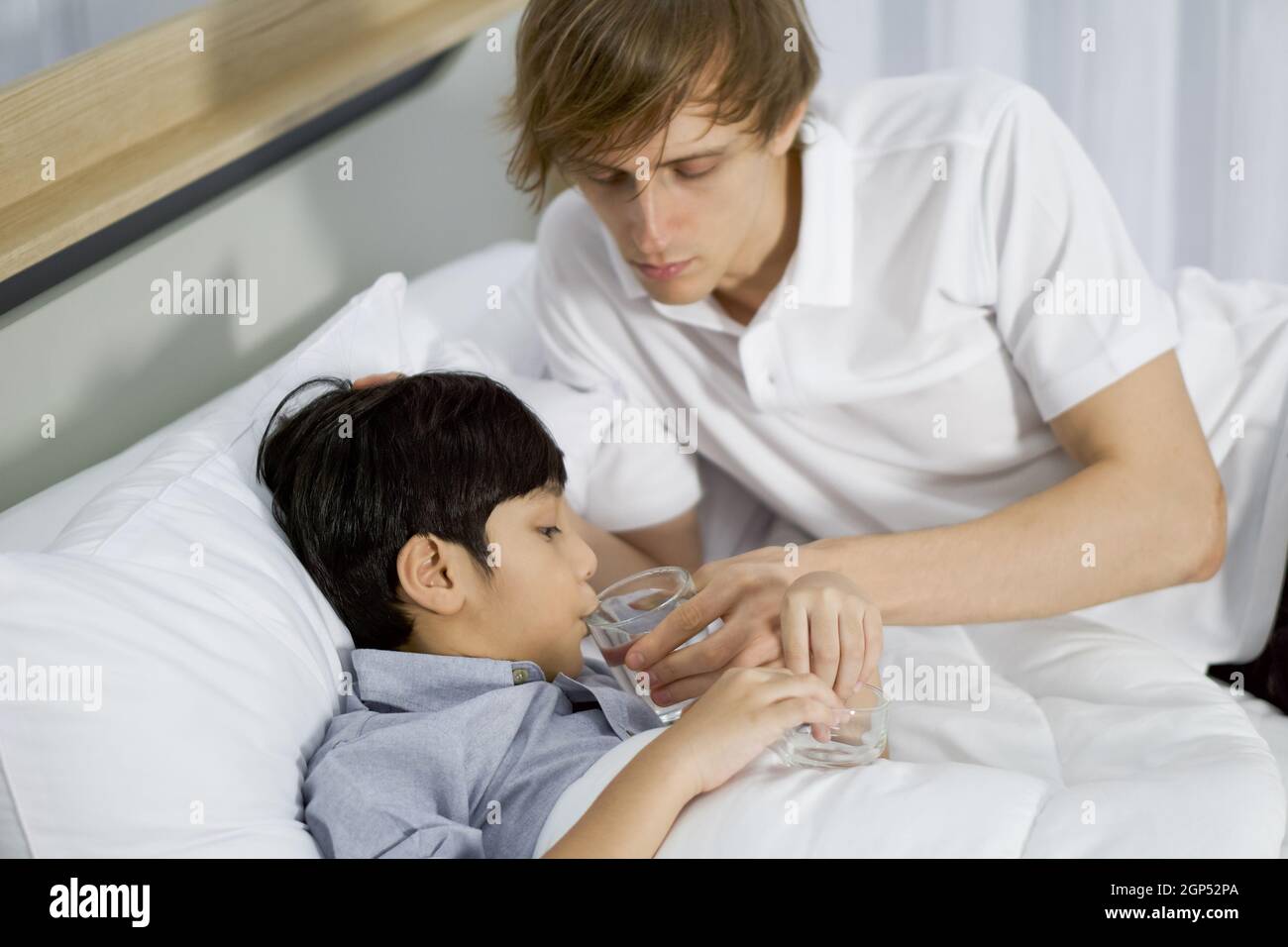 Young father takes care of his sick adopted son in bed. The boy tried