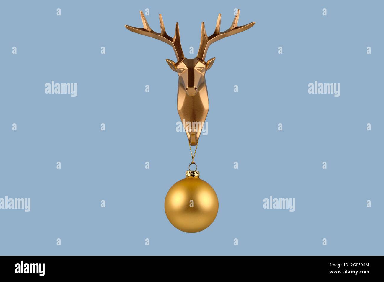 Creative Merry Christmas and New Year concept. Golden deer head with Christmas ball on blue background. Minimal design with copy space. Greeting card. Stock Photo