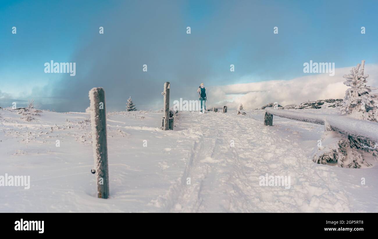 People hiking through a winter landscape in cold and snow under blue sky Stock Photo