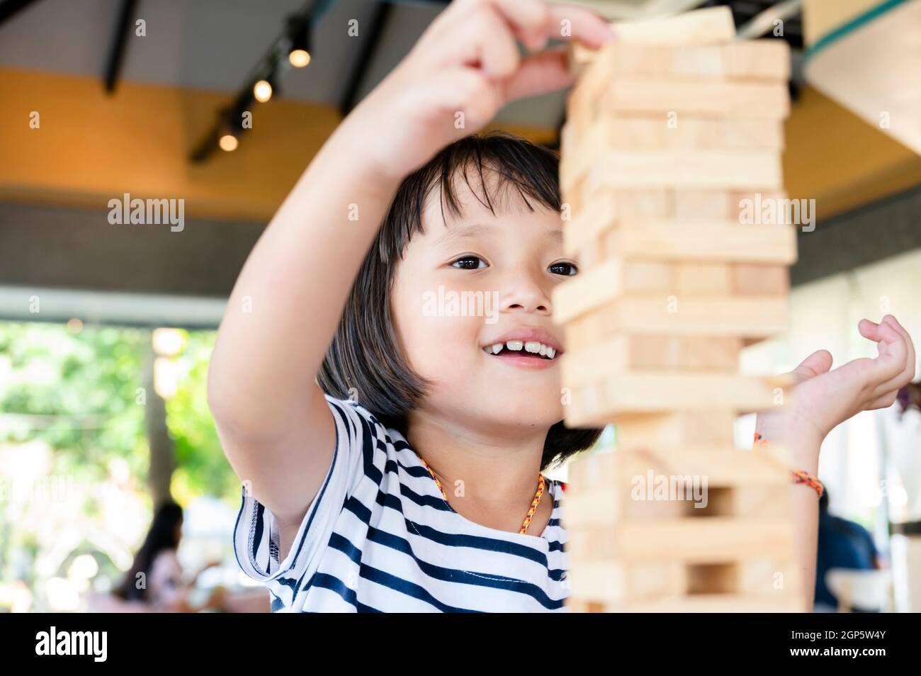 Little cute kid is playing Jenga wooden blocks game. Having fun and learning creativity Stock