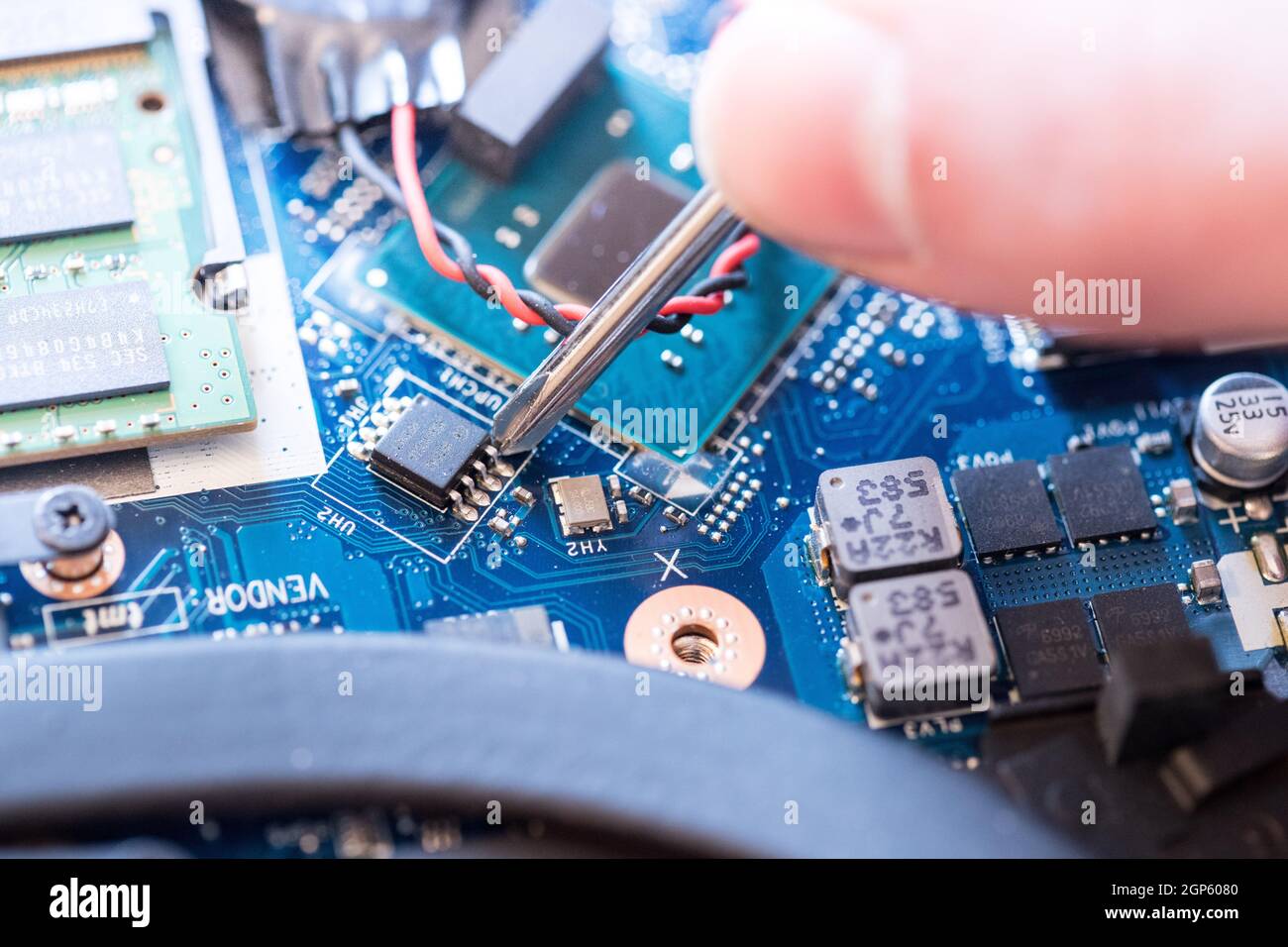 Computer circuit board, hand and screwdriver: Technician is fixing a motherboard. Stock Photo