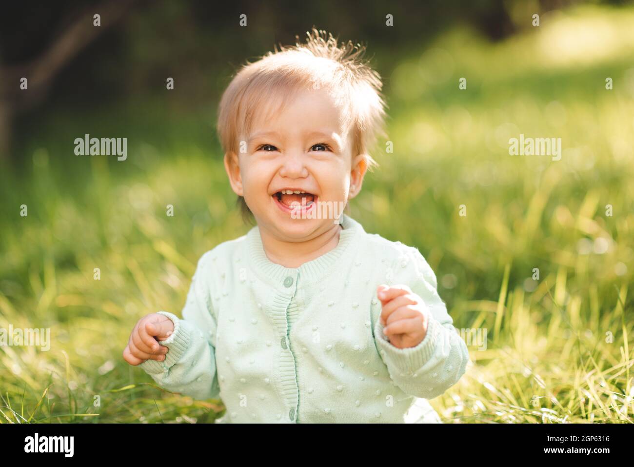 Cute laughing blonde baby girl 1 year old wear knit sweater top having