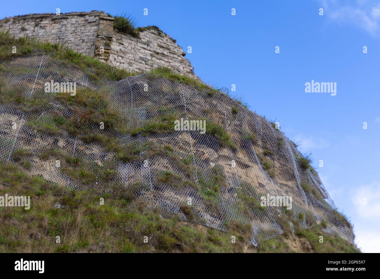 Nets on the headland at Scarborough are used to stop falling rocks. Stock Photo