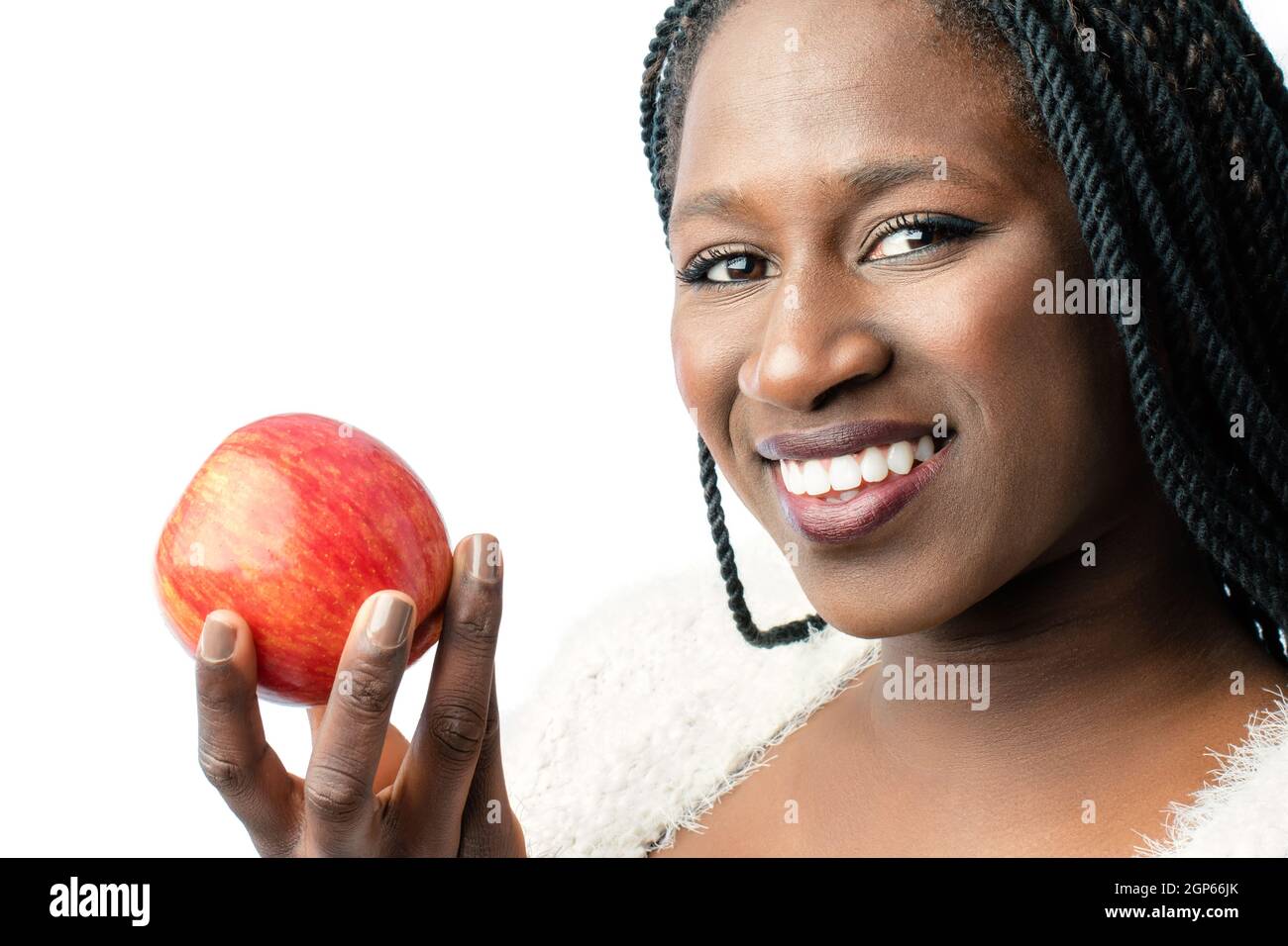 Macro close up of attractive african girl with toothy smile holding red apple. Isolated on white background. Stock Photo