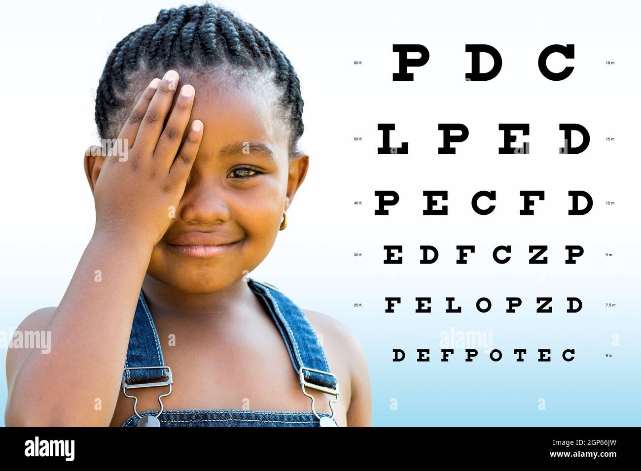 Close up portrait of Little african girl testing eyesight. Girl with braided hairstyle closing on eye with hand. Vision chart with block letters in ba Stock Photo