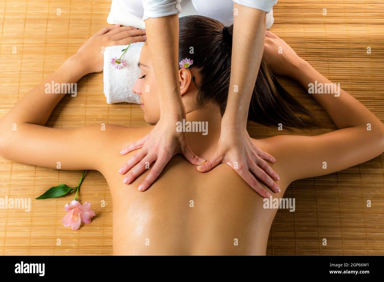 Close up top view of attractive woman enjoying healing back massage.Woman relaxing in low candle light atmosphere. Stock Photo