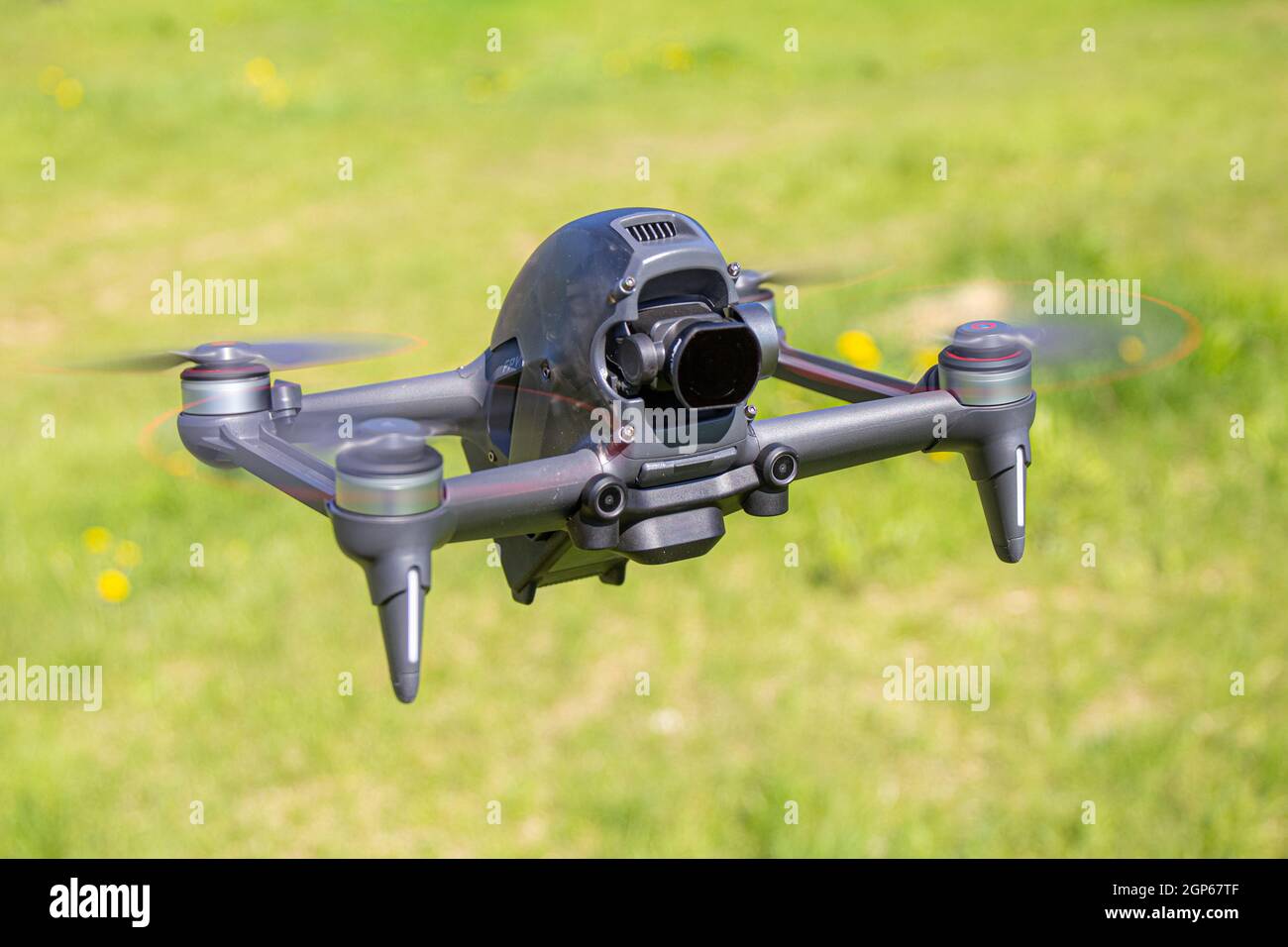 New FPV drone is flying during a sunny day on grass in beckground. Top Front View. Headless Quadcopter with Digital 4K 60 fps camera and Remote Contro Stock Photo