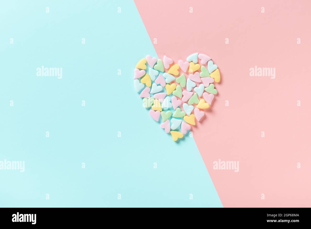 concept of Valentines day greeting with split heart shape from sprinkles over pink and blue background Stock Photo
