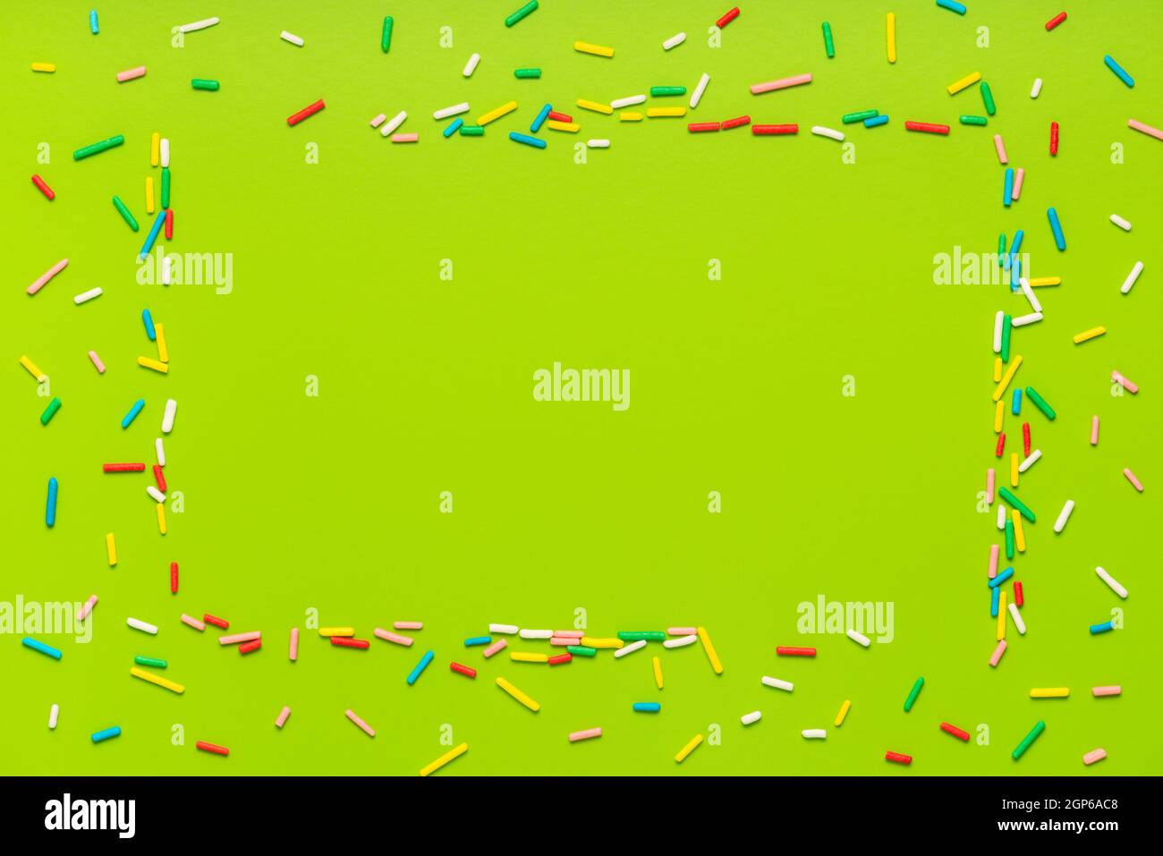 trendy frame of colorful sprinkles over green background, decoration for holiday Stock Photo