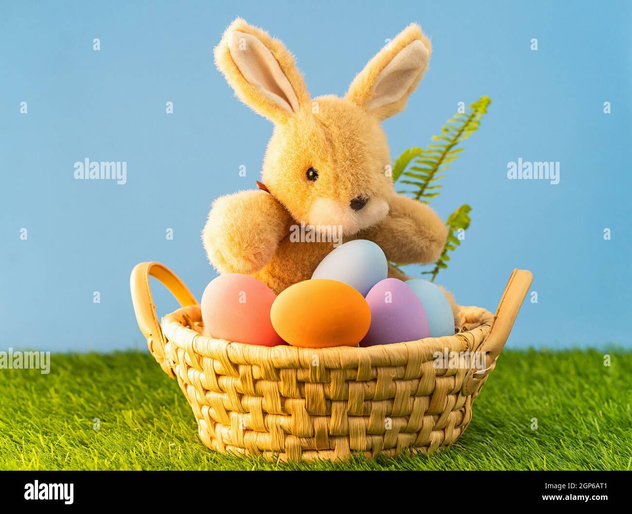Easter bunny toy and Easter eggs in basket on green grass Stock Photo ...