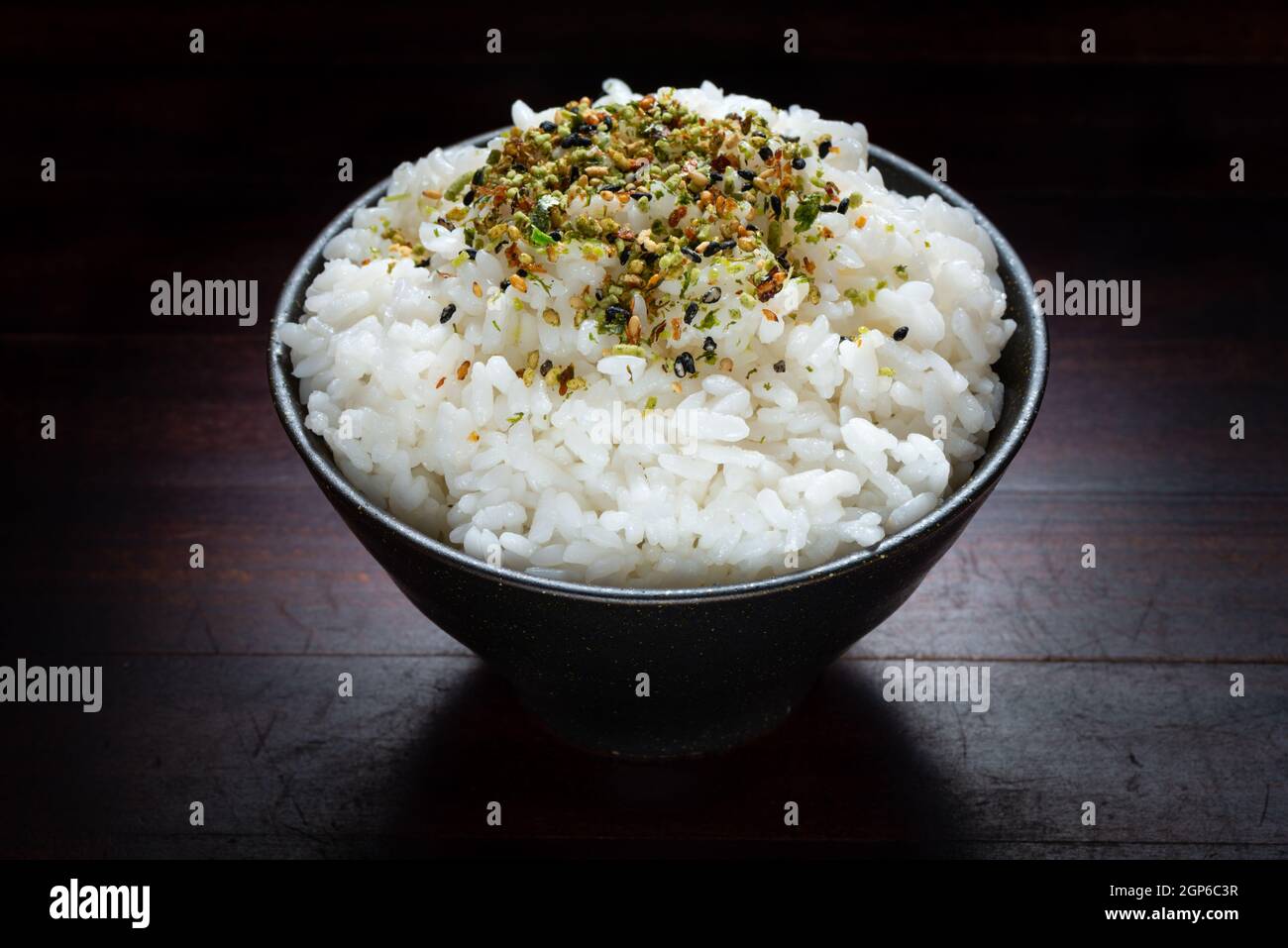 close up rice with Japanese spices in black bowl on wooden background Stock Photo