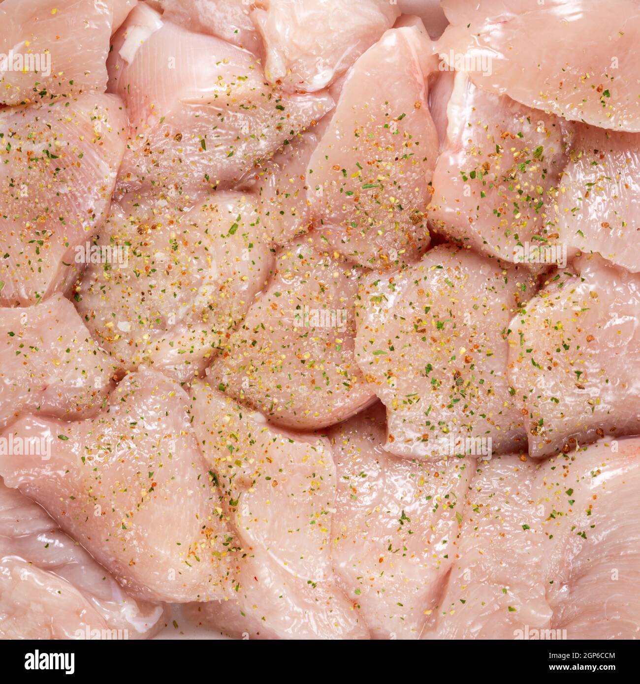 Raw chicken fillet chunks with spices top view, background Stock Photo