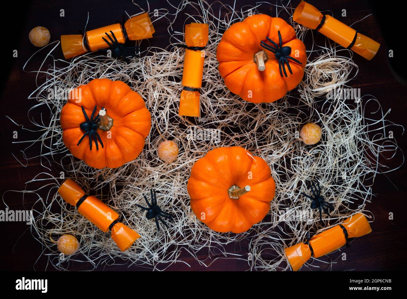 pumpkins, candies, spiders and straw over black background, concept of Halloween party, top view Stock Photo