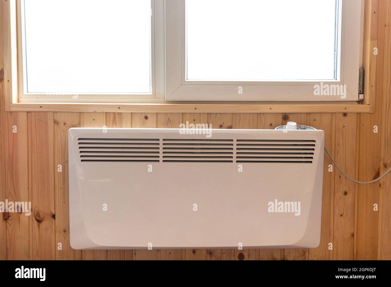 Electric radiator under the window of a country house whose walls are ...