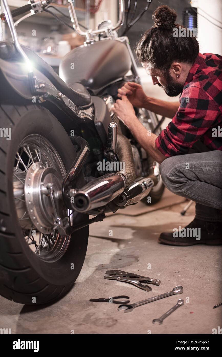 Vertical shot of a German male repairing his motorcycle. Stock Photo