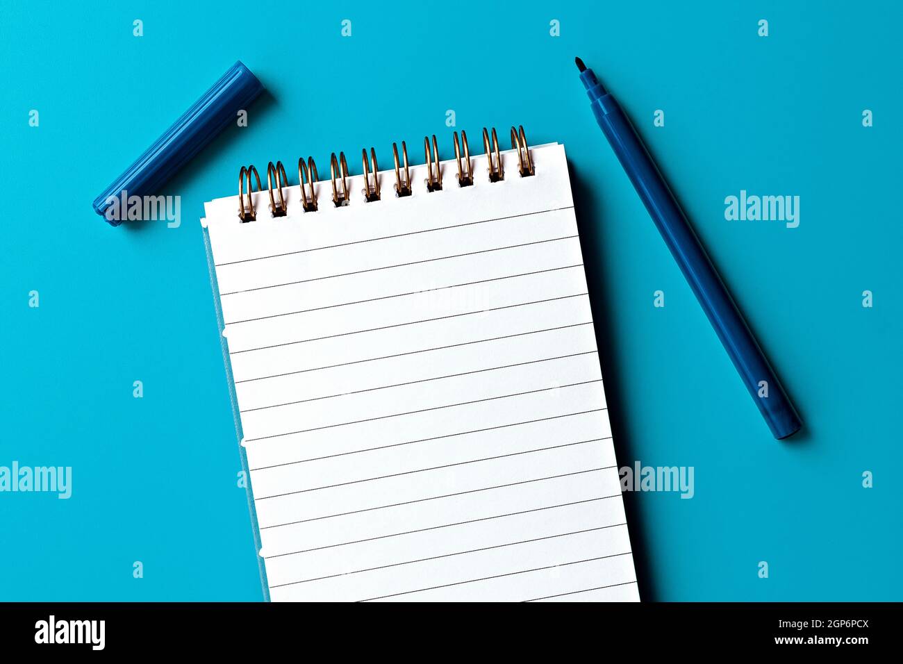 template for text and design. empty white notepad and one marker on blue background Stock Photo