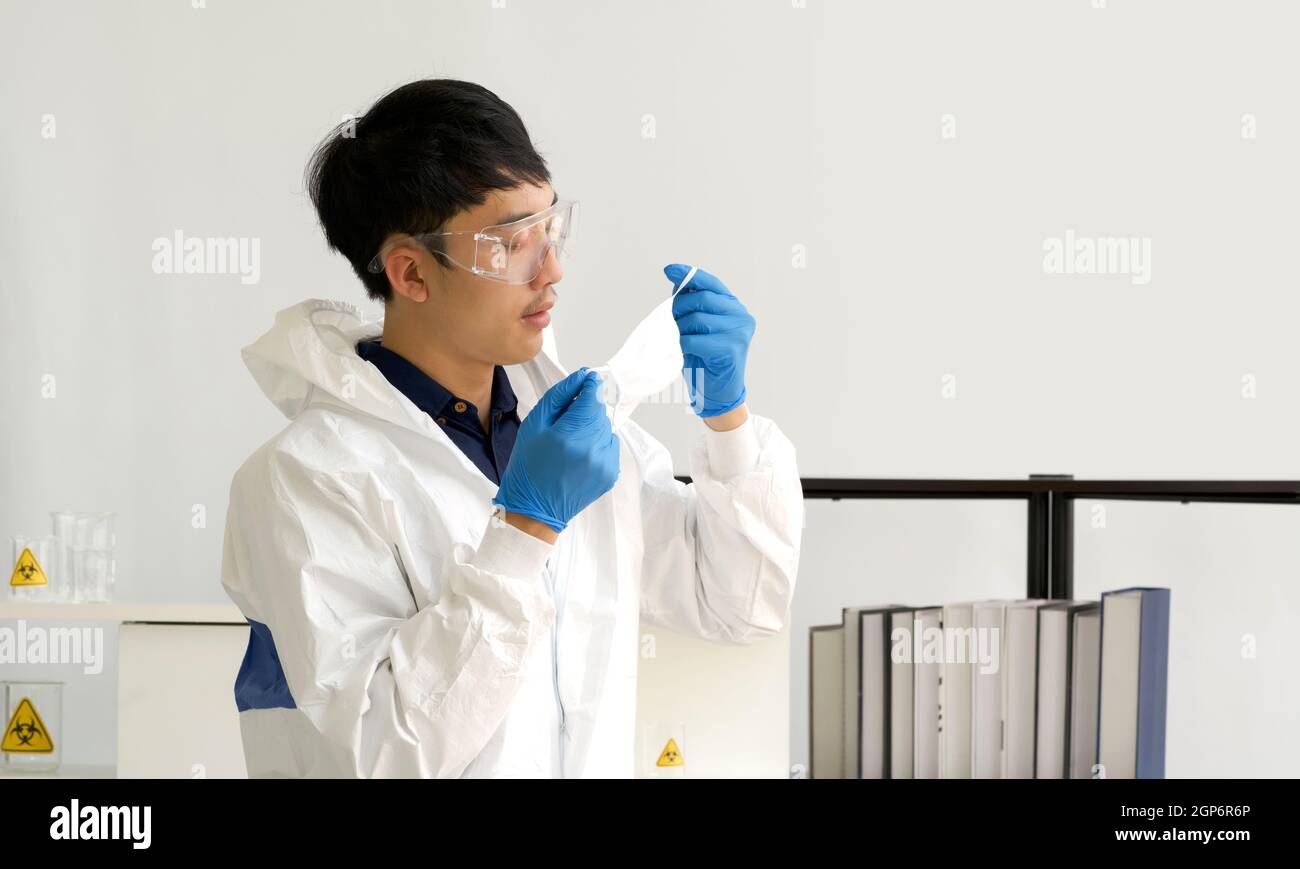 Asian scientist inspect the quality of a mask before beginning the experiment in a scientific laboratory. Stock Photo