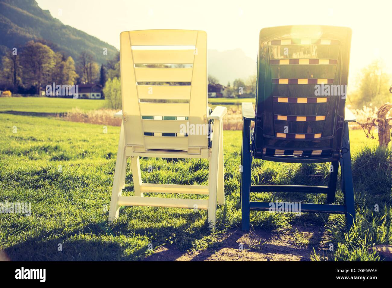 Plastic deck chairs in the own garden, summertime in dusk Stock Photo
