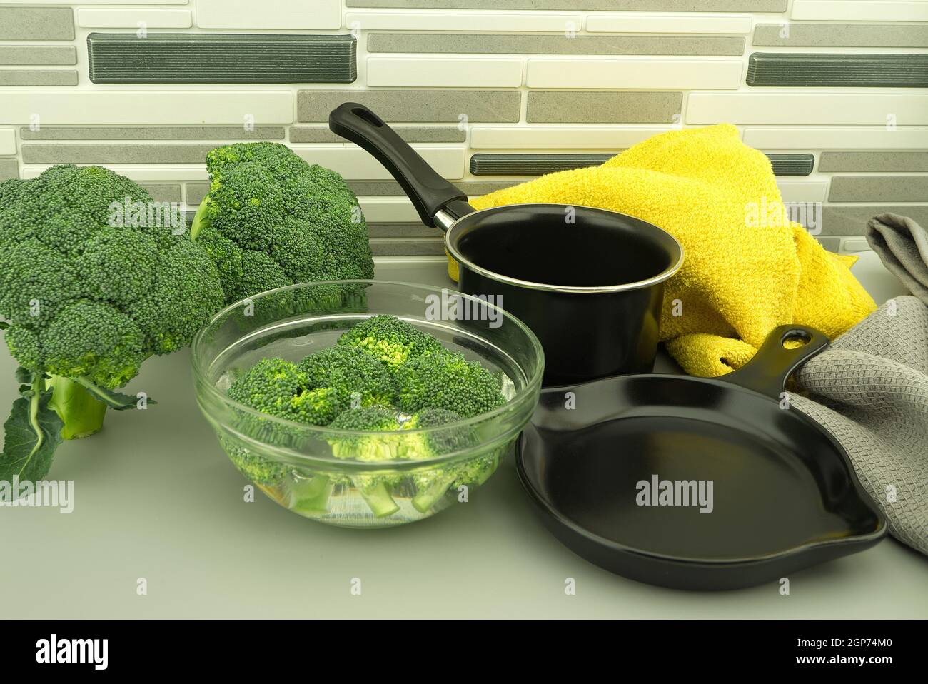 Fresh broccoli florets soaked in a clear bowl of water next to the pan ...