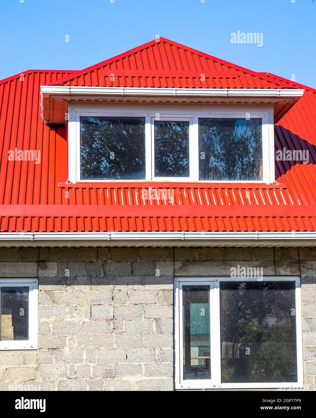 House with plastic windows and a red roof of corrugated sheet