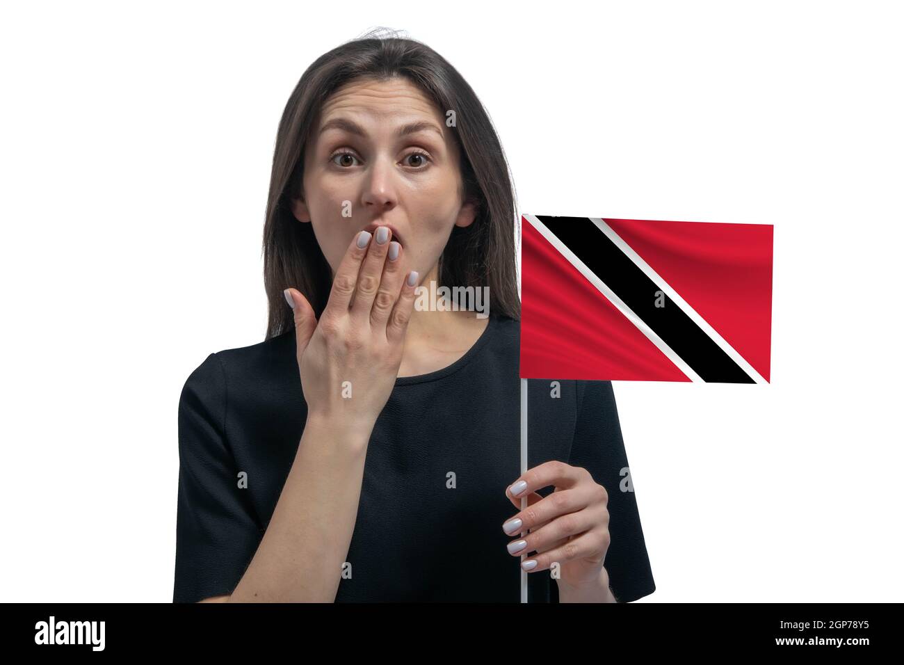 Happy young white woman holding flag of Trinidad and Tobago and covers her mouth with her hand isolated on a white background. Stock Photo